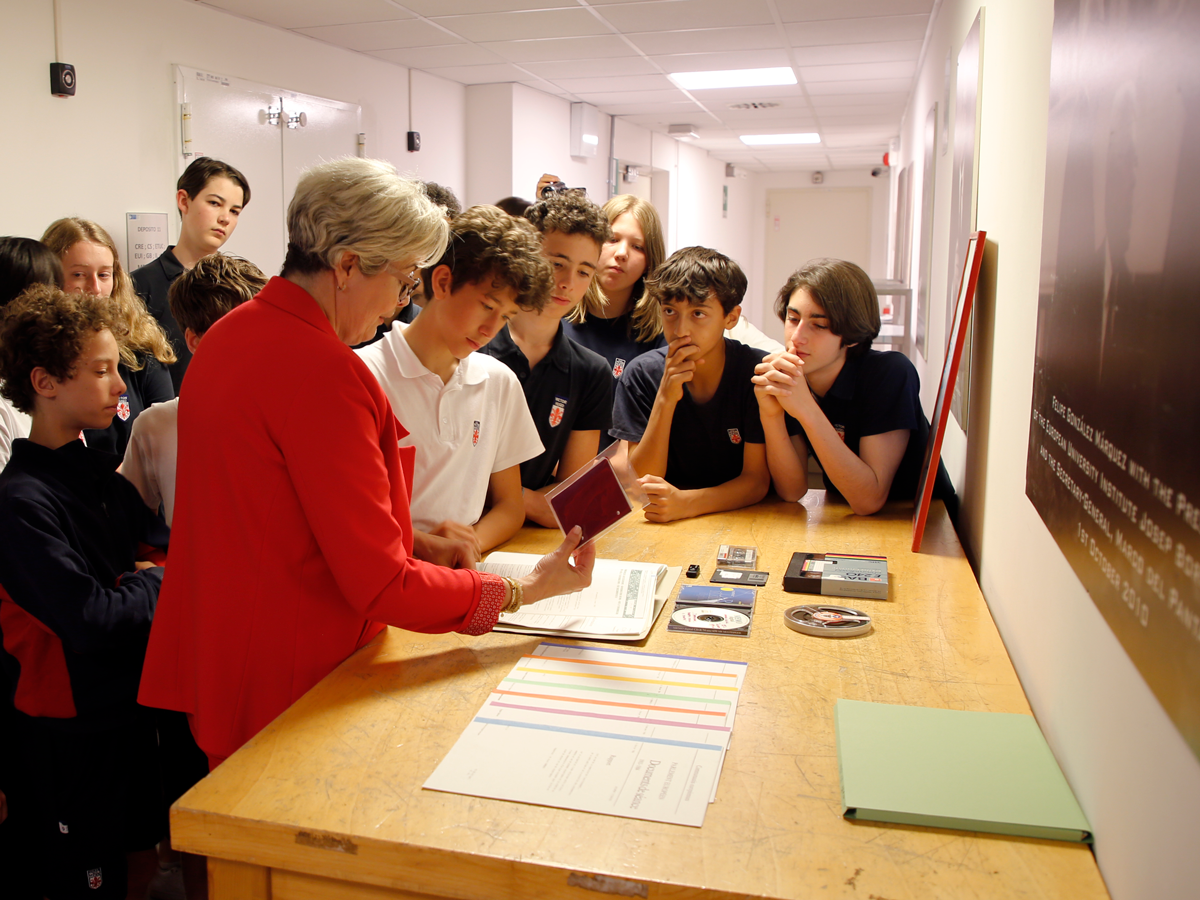 An archivist demonstrates documents and artefacts to students visiting the HAEU archival vaults.
